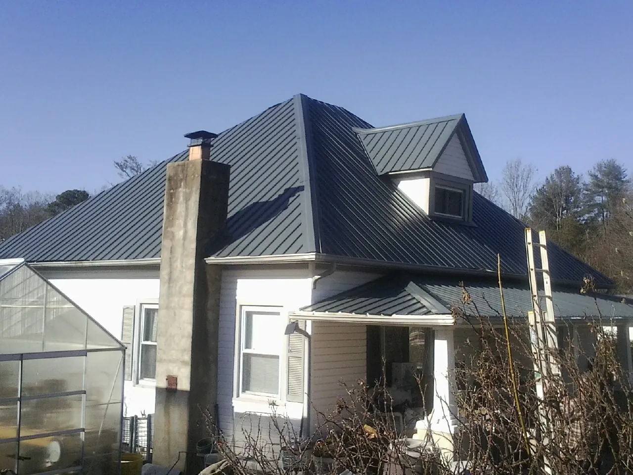 Dark blue standing seam metal roof on a white farmhouse with dormer — Slate & Tile Roof Repair by Roofing Brothers in Moorefield