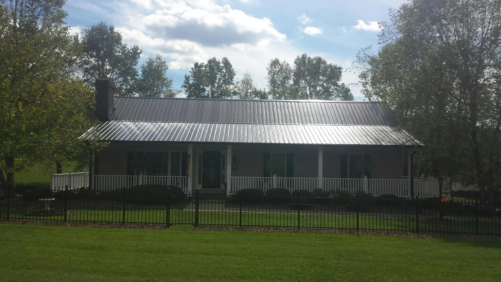 Gray metal roof on a brick ranch with a full width front porch — Gutter Guard Installation work by our crew in Moorefield
