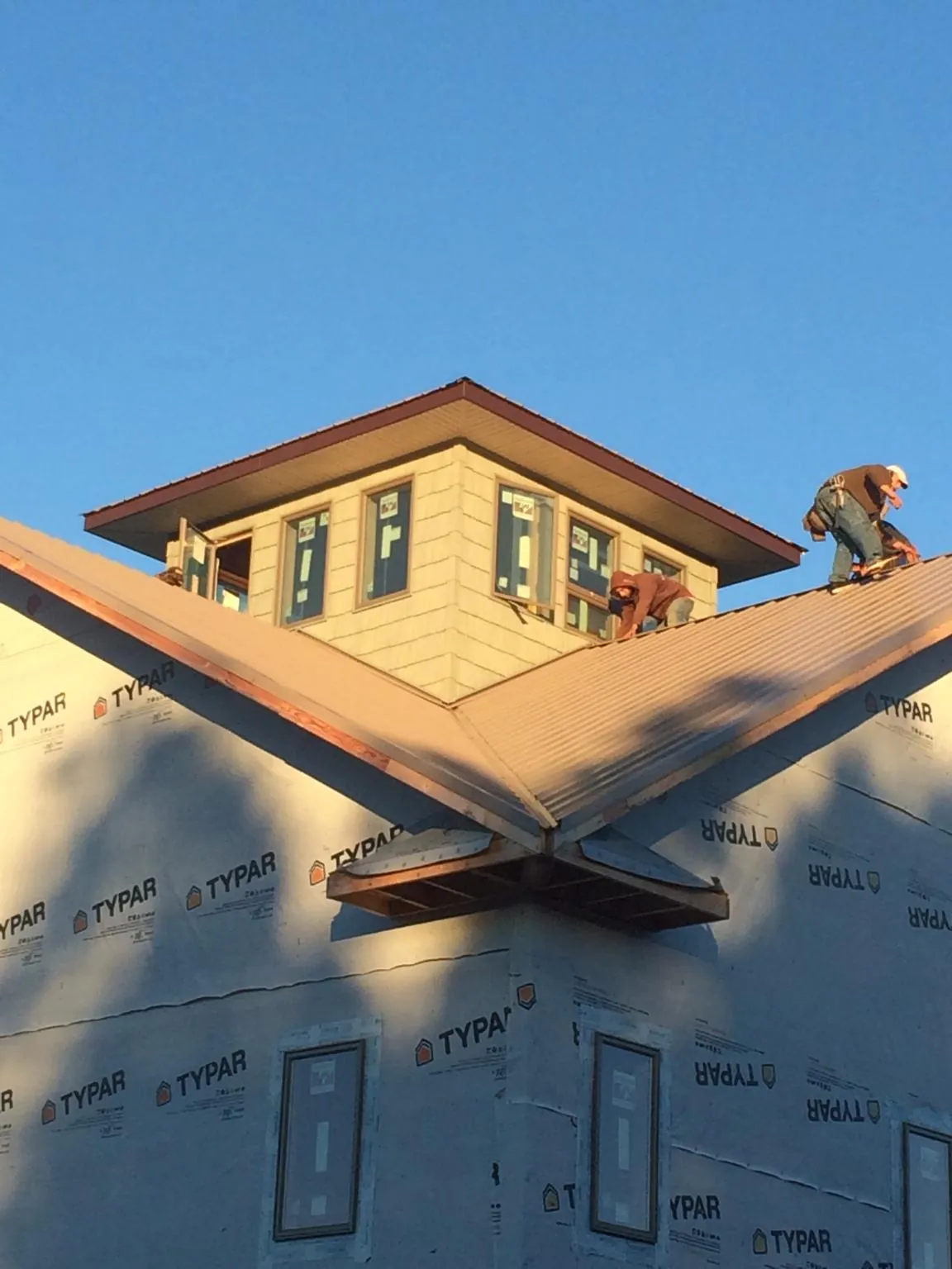 Roofers working around a rooftop cupola on a new metal roof at sunset — Roof Waterproofing in Moorefield by Roofing Brothers